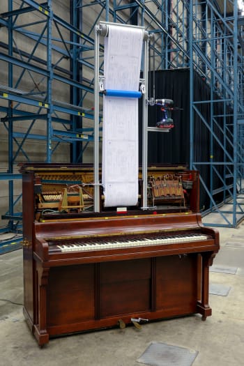 Domas van Wijk's artwork, on display at Art Rotterdam's Prospects, features a modified player piano with a long roll of paper extending from it.