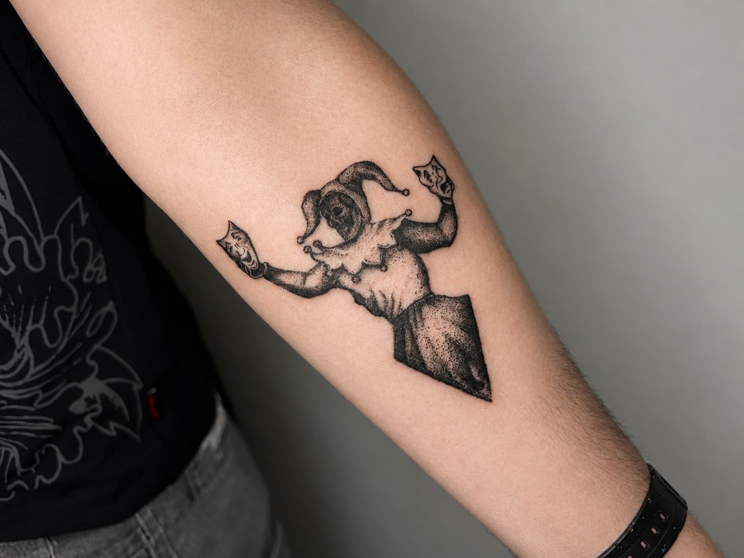 Dotworkowy tatuaż błazna z kartami na przedramieniu — blackwork, Parvata Tattoo Wrocław