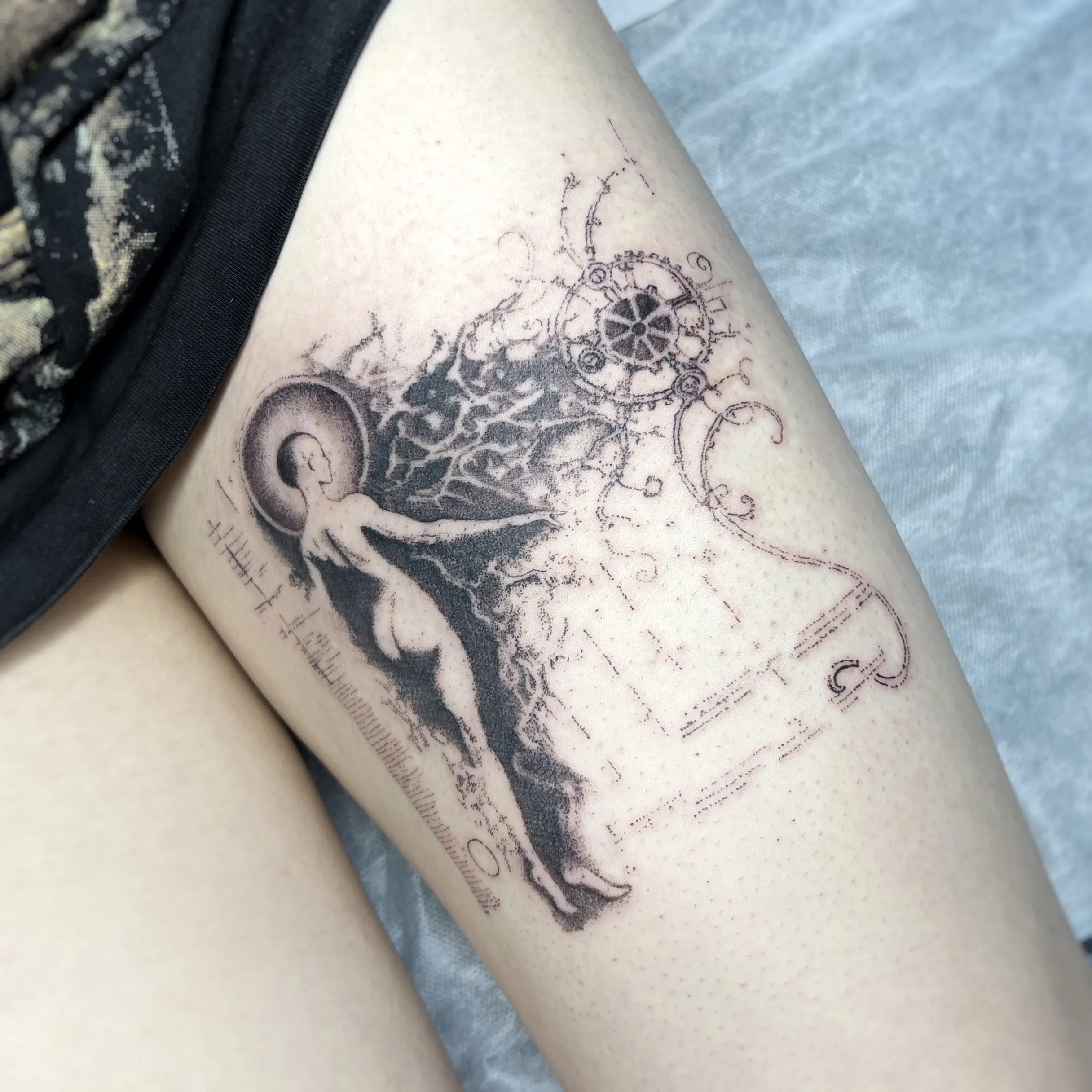 Tatuaż przedstawiający postać unoszącą się w stronę geometrycznego symbolu wykonany techniką dotwork.
