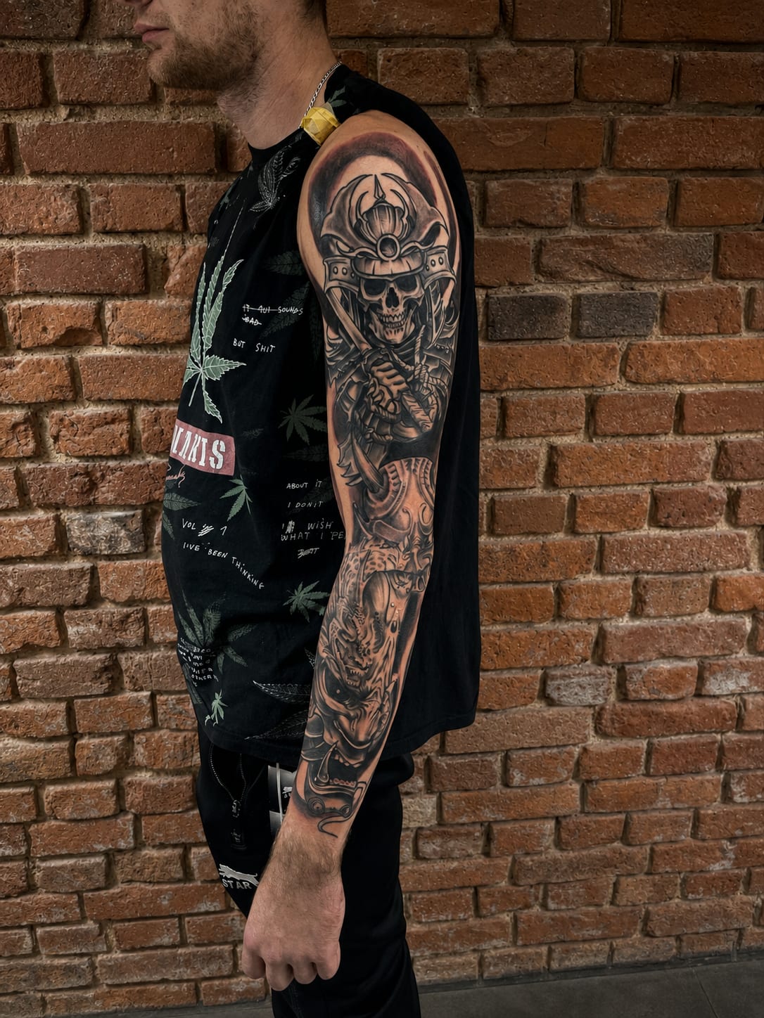 Czarno-szary tatuaż na rękawie z czaszką samuraja w hełmie i maską demona Oni.