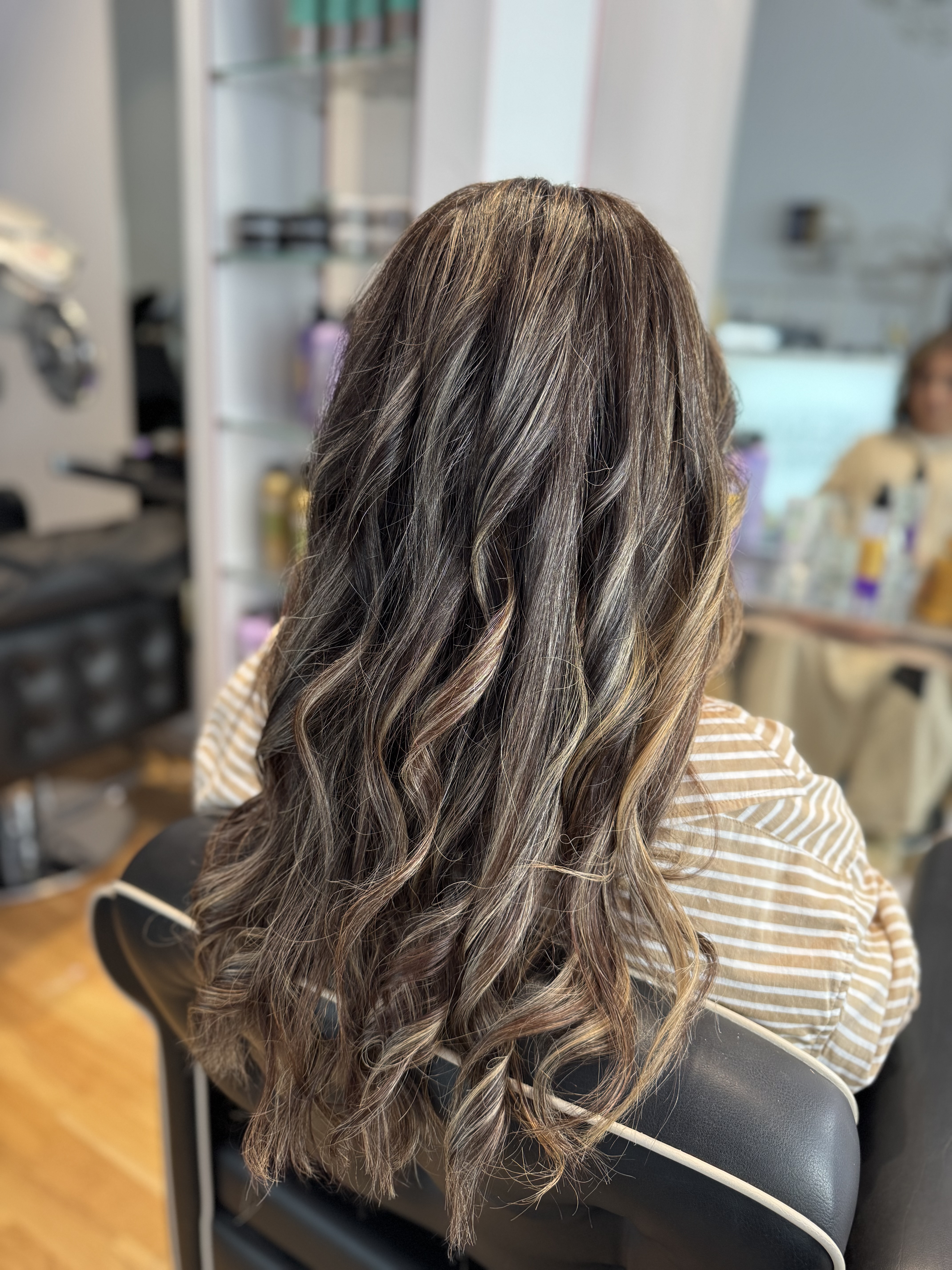Beigebrun balayage med ljusare slingor och mörkare djup i långt, vågigt hår