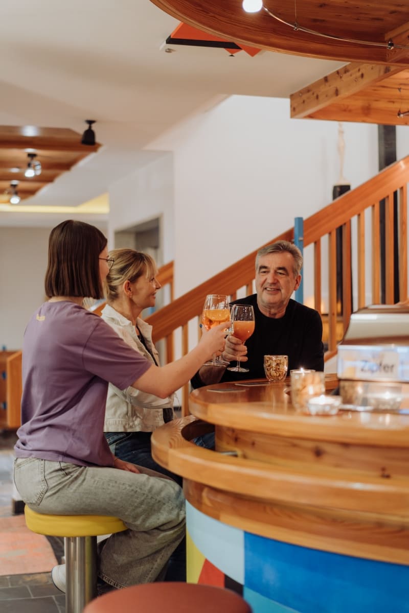 Freunde stoßen in der Bar des Glemmtalerhof in Hinterglemm an und genießen die gesellige Atmosphäre.