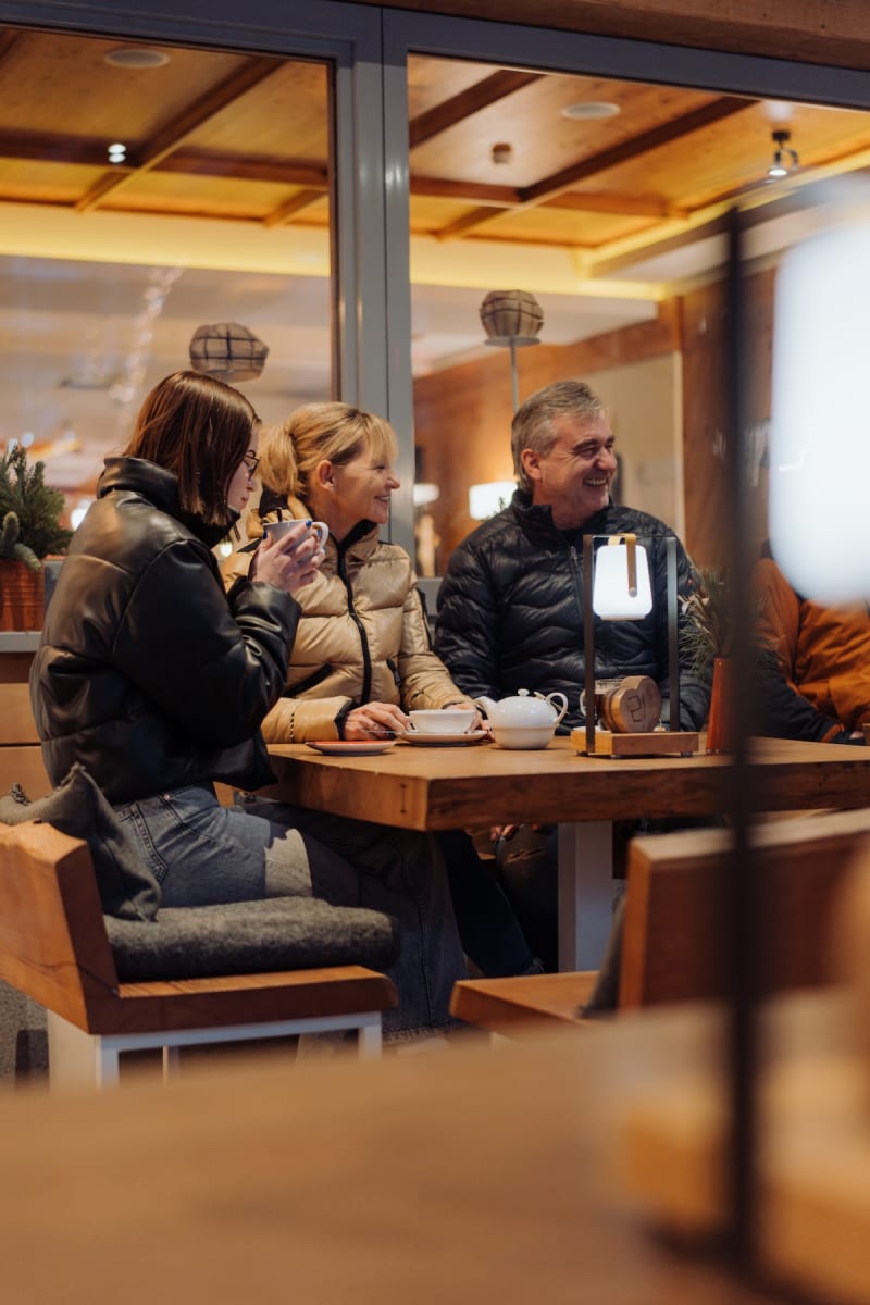 Freunde sitzen am Tisch im Glemmtalerhof in Hinterglemm und genießen Getränke in gemütlicher Atmosphäre.