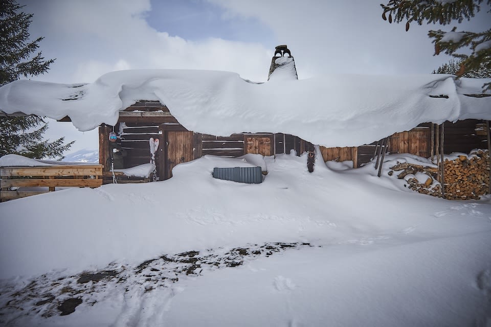 Der Glemmtalerhof in Hinterglemm ist unter einer dicken Schneedecke verborgen, umgeben von winterlicher Landschaft.