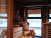 Zwei Personen entspannen in der Sauna im Glemmtalerhof in Hinterglemm mit Blick auf das Glemmtal.