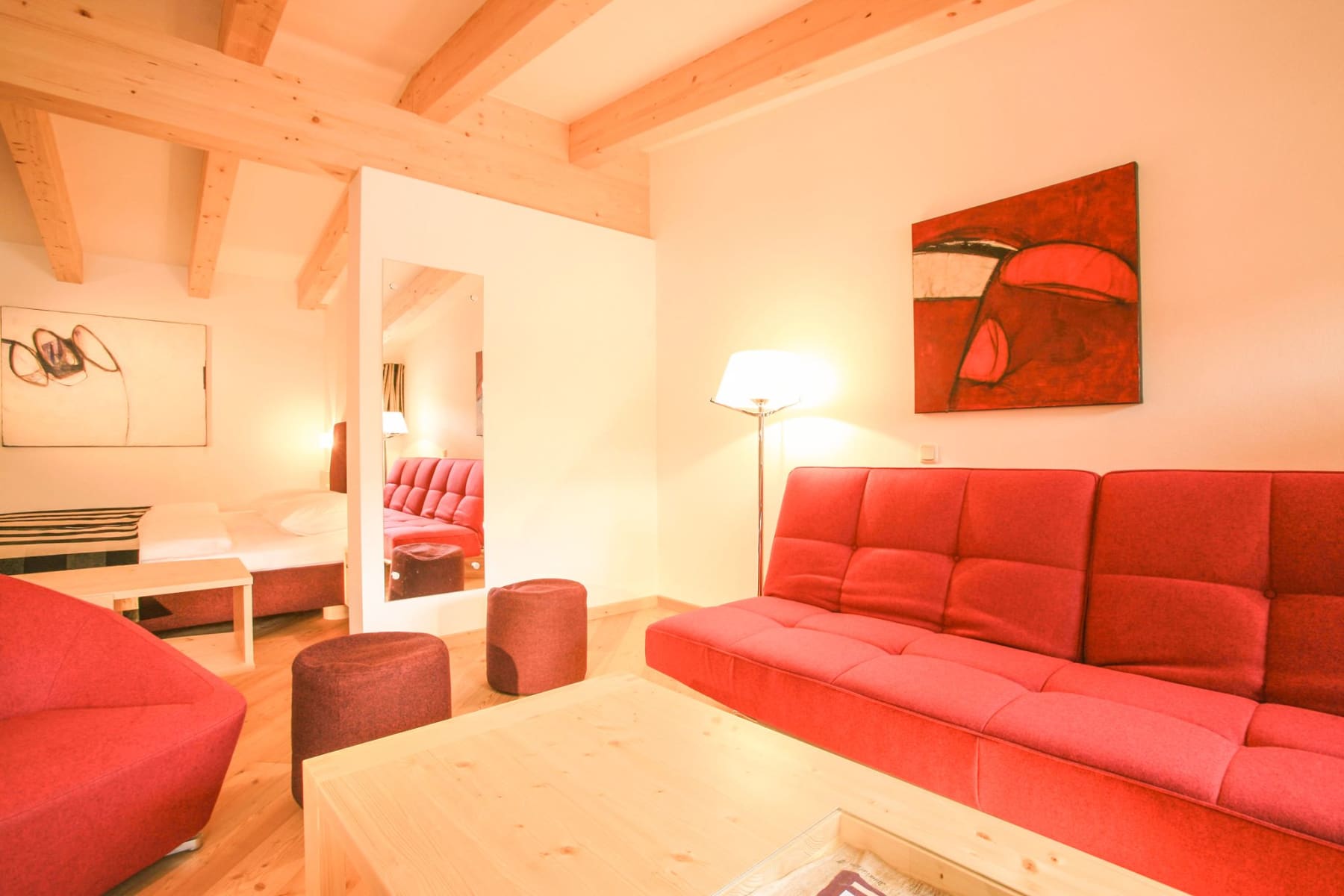 Ein modernes Zimmer im Glemmtalerhof in Hinterglemm mit roter Couch und Holzdecke.