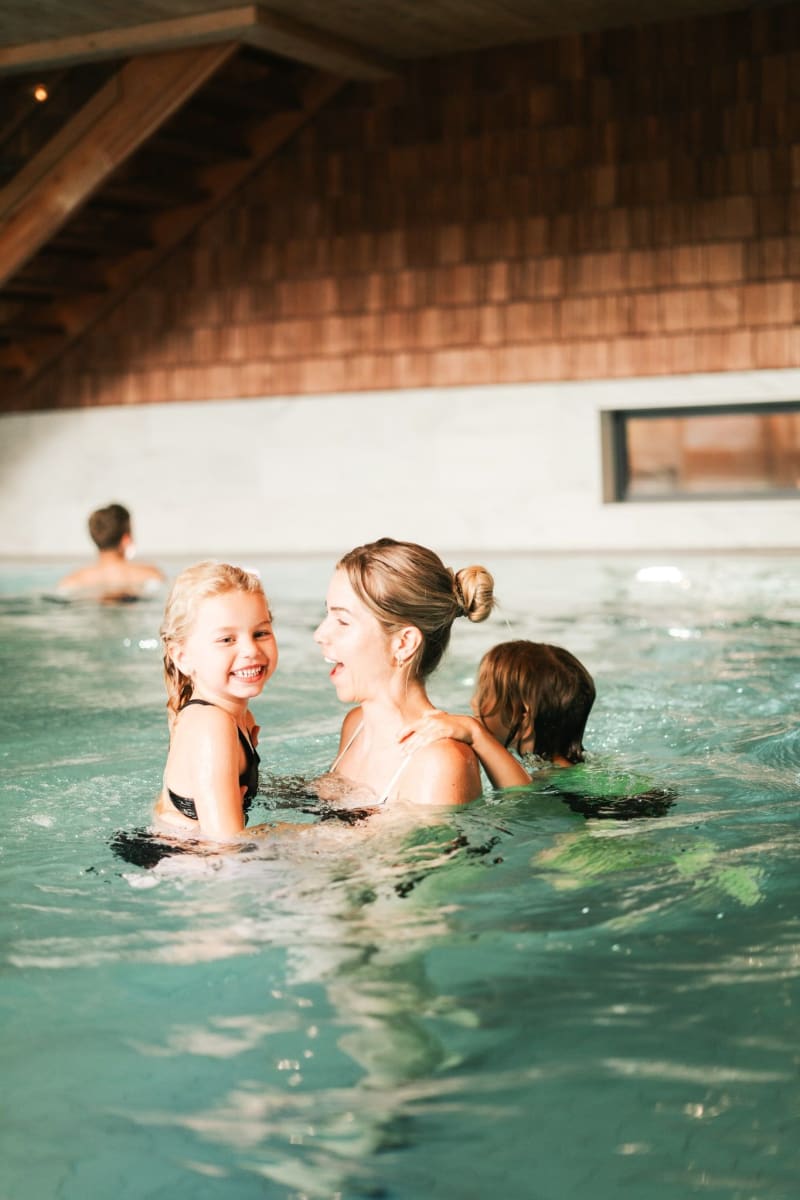 Eine Mutter genießt Zeit im Wasser mit ihren fröhlichen Kindern im Glemmtal.