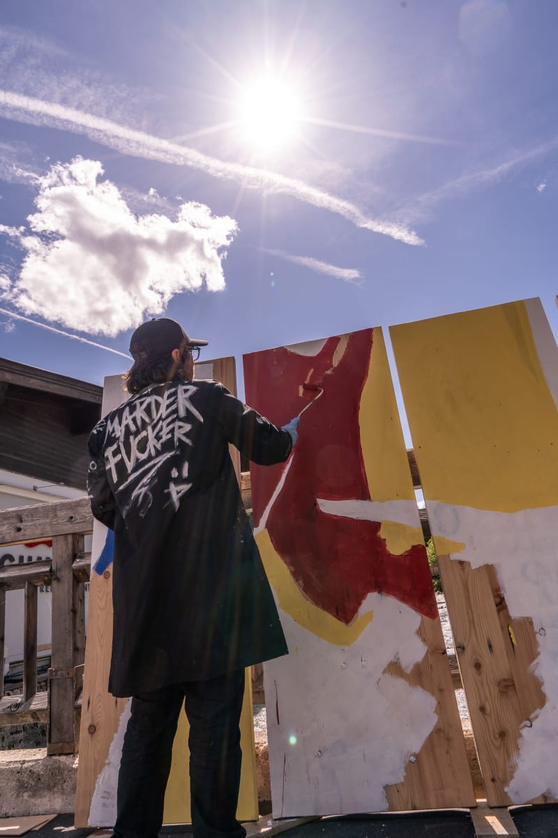 An artist paints on a wall in the Glemmtal under the sun.