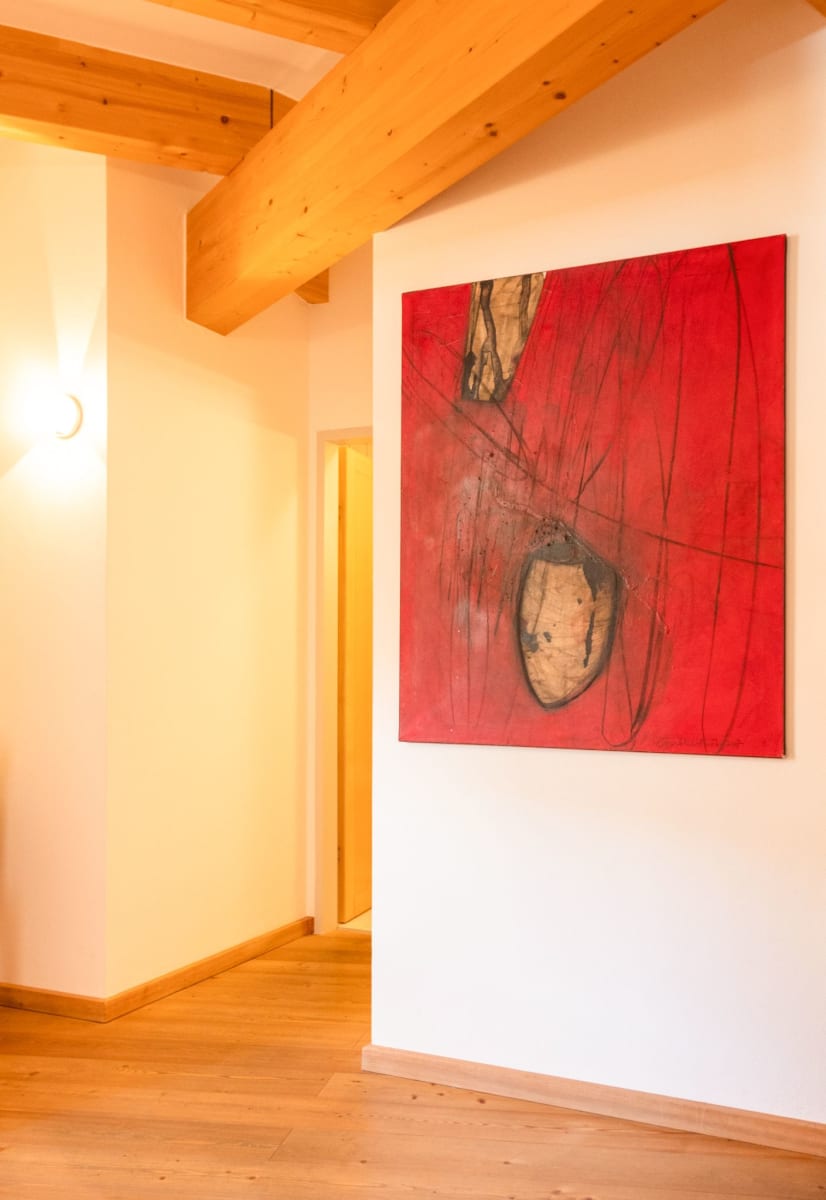 A red painting on the wall in Glemmtalerhof, warm wood and inviting atmosphere.