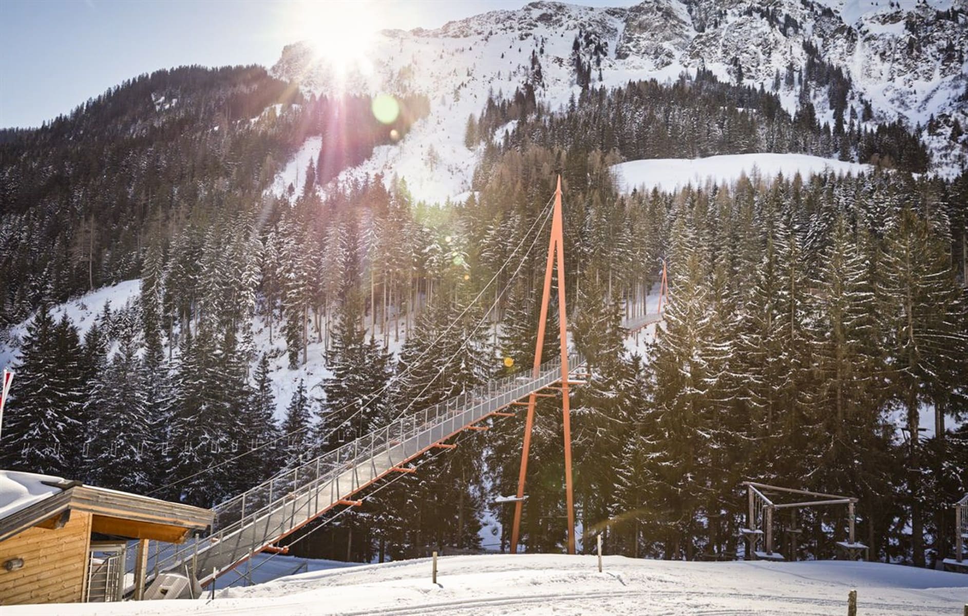 Schneebedeckte Berge und Bäume im Glemmtal mit einer beeindruckenden Fußgängerbrücke