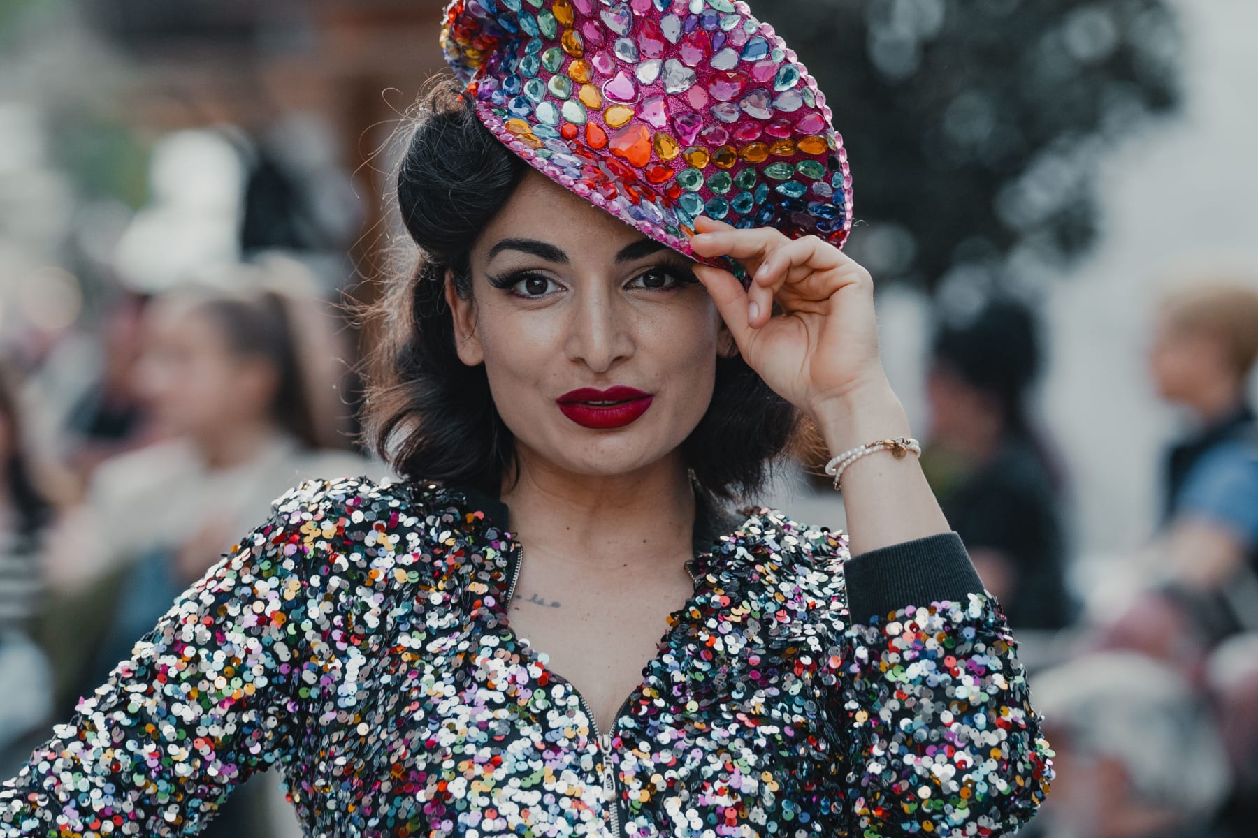 A woman in a colorful glitter outfit poses and smiles. Glemmtal offers an exciting atmosphere.