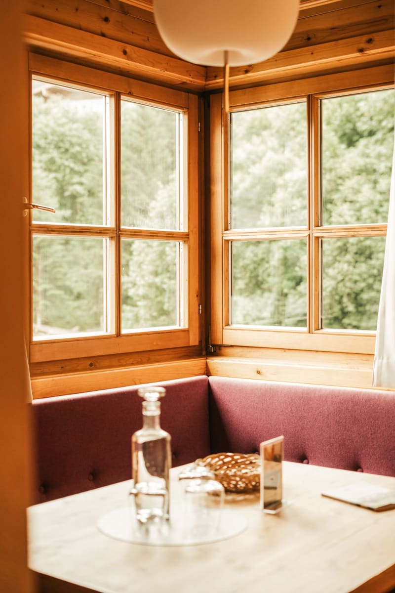 Ein gemütlicher Tisch im Glemmtalerhof mit Ausblick auf die grüne Landschaft. DE
