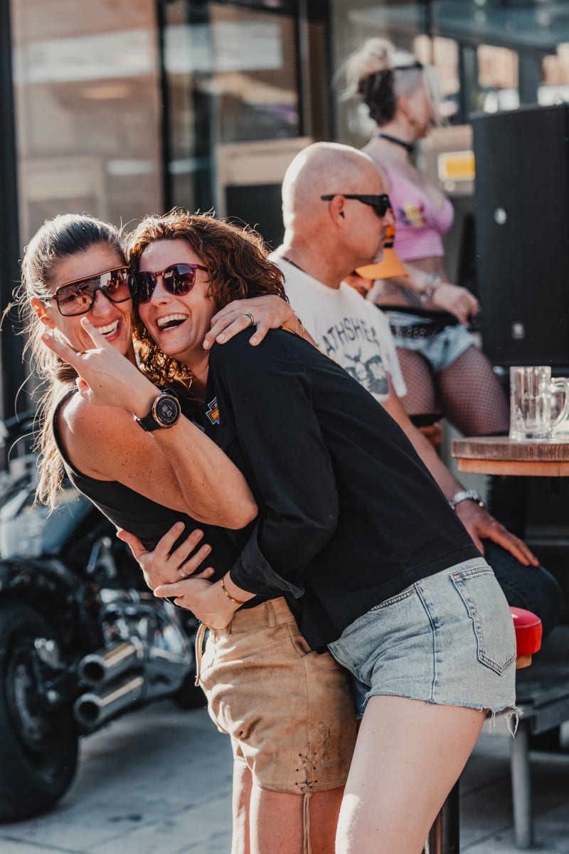 Two women happily embrace in front of Glemmtalerhof in Hinterglemm.
