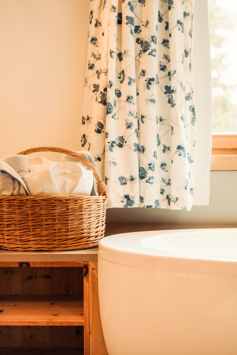 Im Badezimmer liegen Handtücher in einem Korb neben einer eleganten Badewanne.