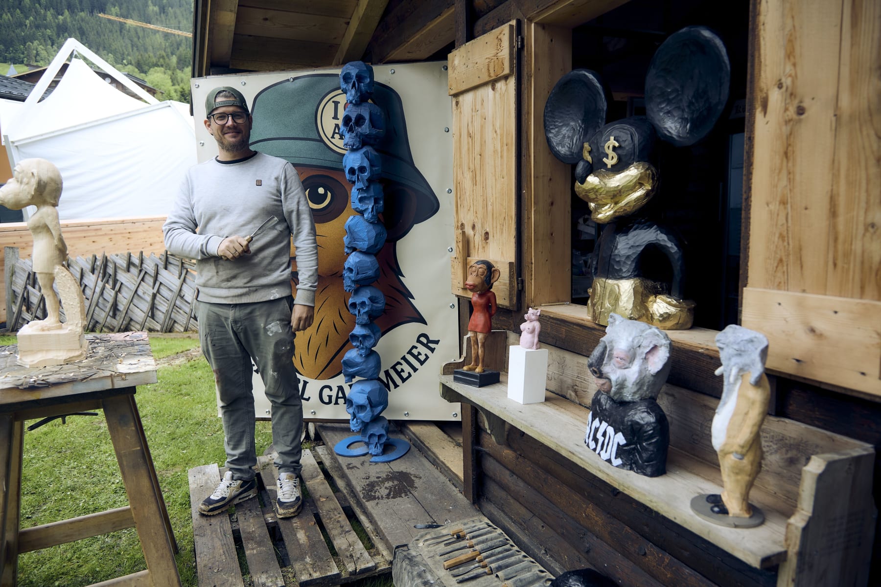 Artist stands in front of wooden sculptures at Glemmtalerhof in Hinterglemm
