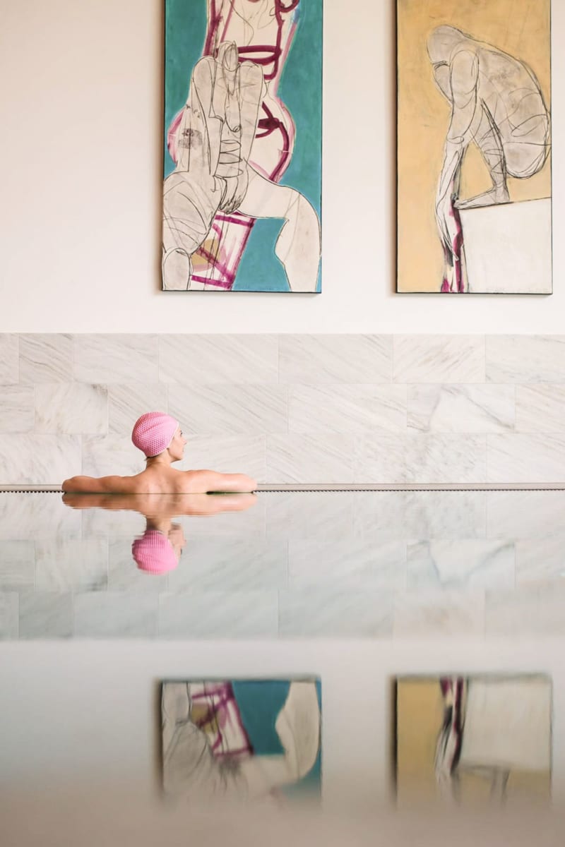 A person relaxes in the water with modern artwork in the background at Glemmtalerhof in Hinterglemm.