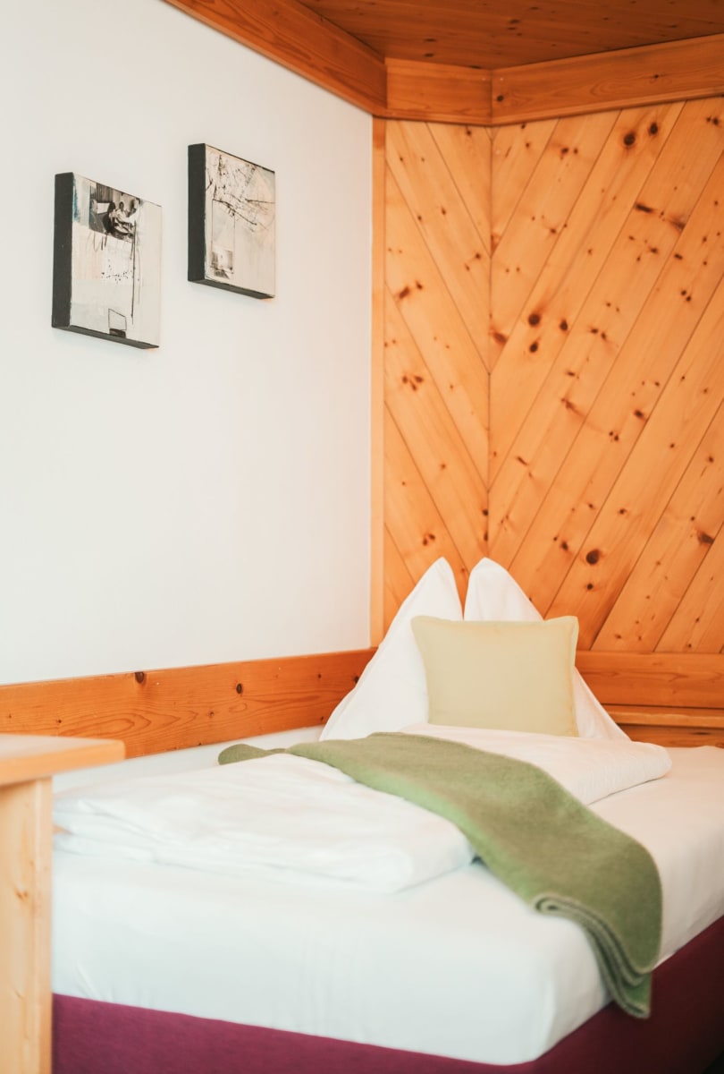 Helles Zimmer im Glemmtalerhof in Hinterglemm mit Holzverkleidung und bequemen Bett.