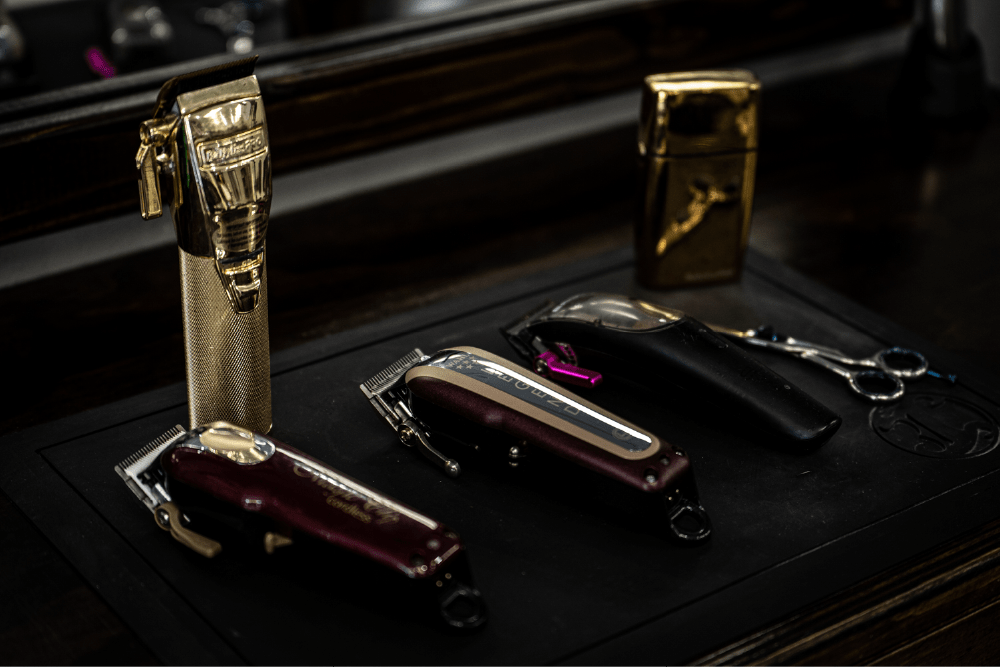 Three electric razors are organized in a row against a dark background. 
						Next to them lie a pair of scissors.