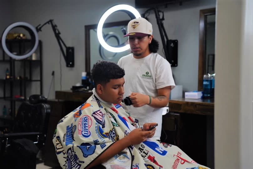 A barber gives the finishing touches to the haircut of his client.