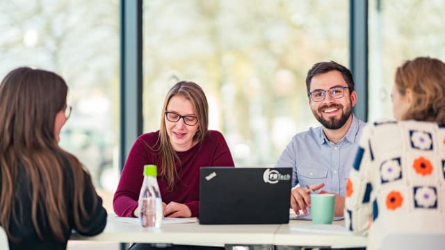 Happy businessman talking with his colleagues in office - FDTech.de