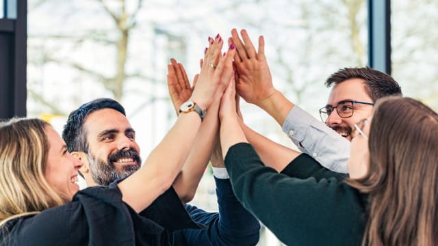 Large group of business colleagues holding their hands in unity  - FDTech.de