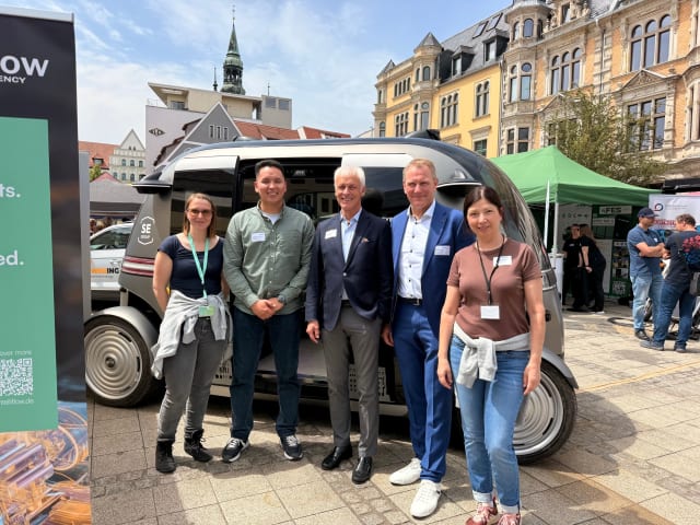 FDTech colleagues and guests standing in front of an autonomous shuttle on the main market square in Zwickau during the SAM Symposium 2026.