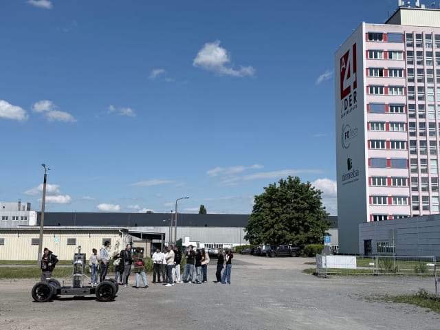 French exchange students standing in front of the PixKit autonomous vehicle in the FDTech parking lot during a live demonstration in Chemnitz.