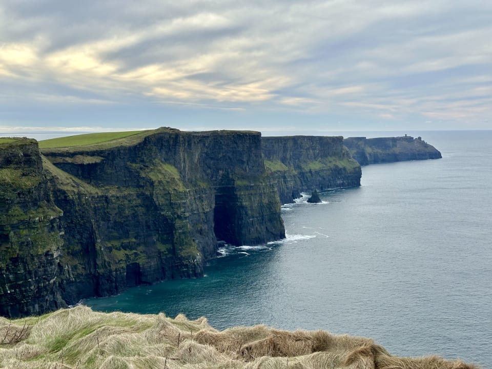 Cliffs of Moher: layered rock faces and green cliff tops above the Atlantic under an overcast sky