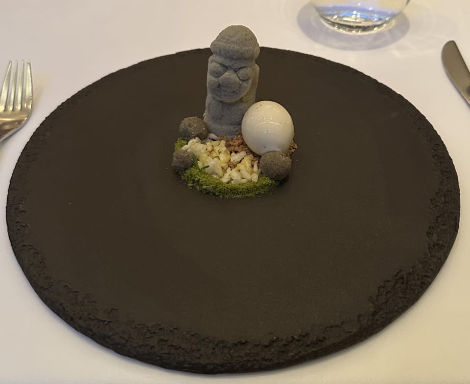 Dolhareubang dessert with moss-like crumbles on a black plate at Jungsik, NYC
