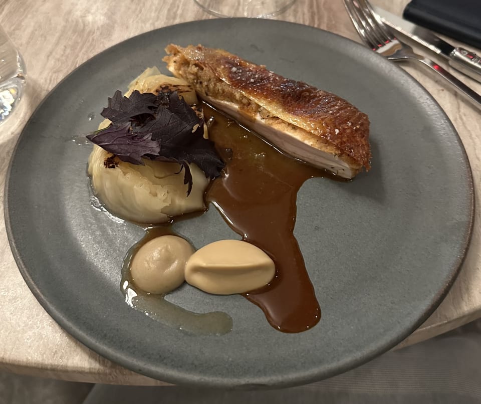 Plated Amish chicken and sides on a dark ceramic plate at BRESCA, Washington DC