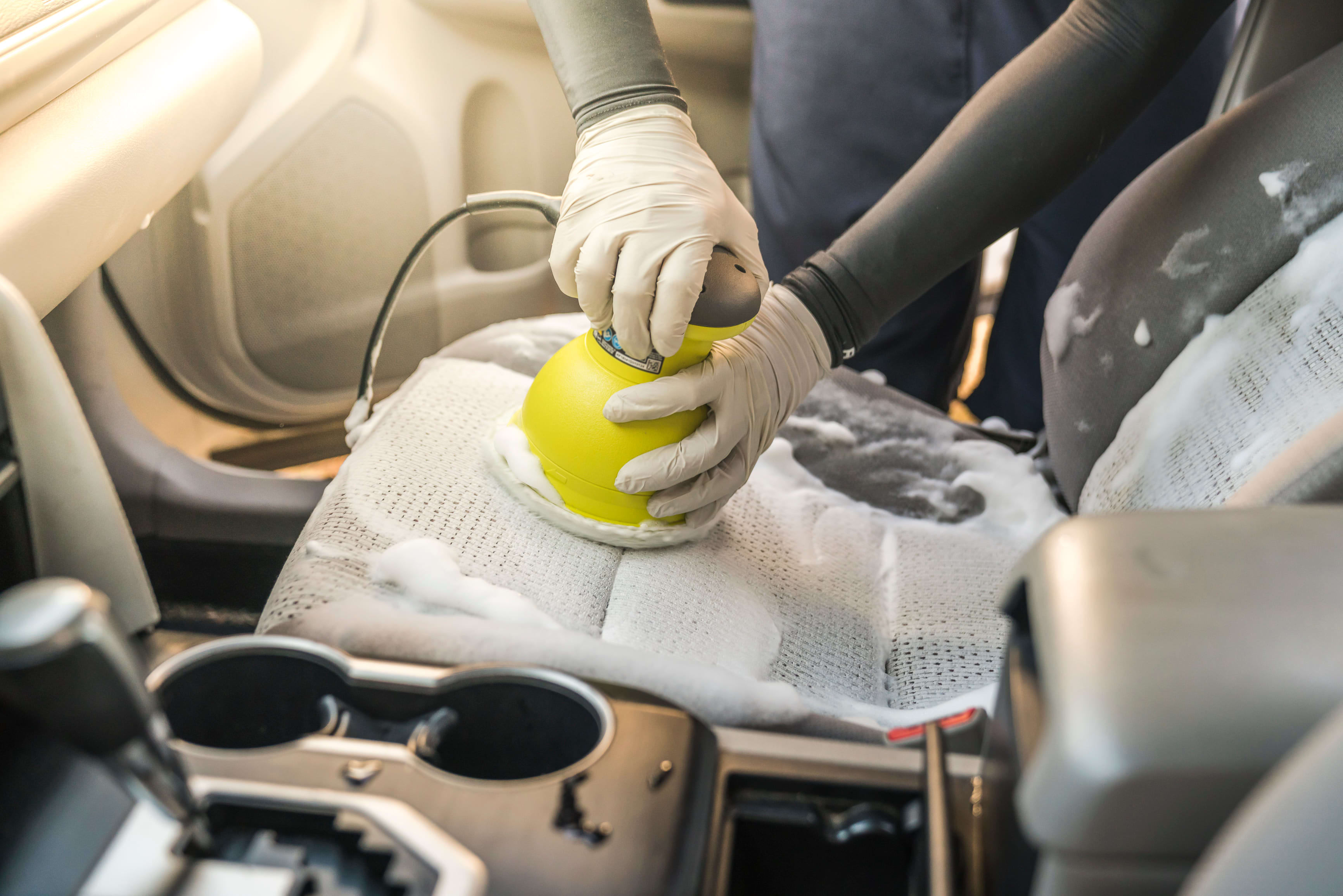 Mujer lavando con espuma el asiento de un carro