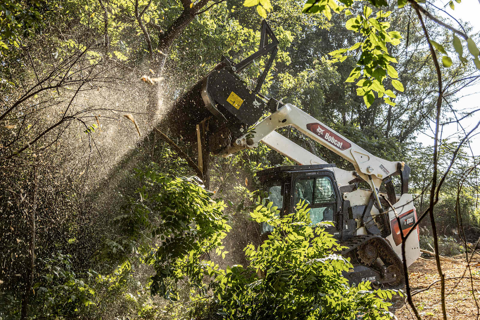 Bobcat T86 compact track loader using a front-mounted drum mulcher on dense vegetation