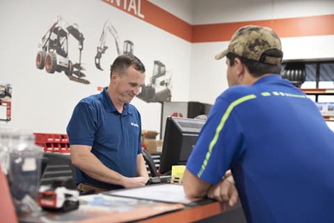 A Bobcat Dealer Representative Talks to a Customer at the Dealership Rental Counter