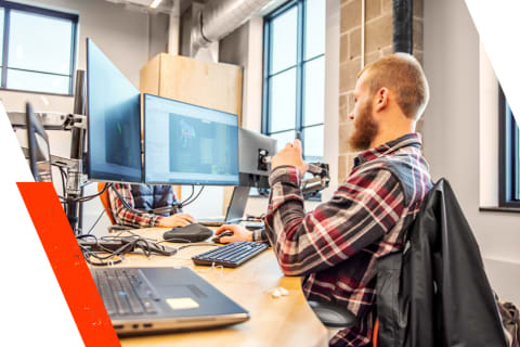 An Engineering Intern In The Student Development Program Works At His Desk Using Two Monitors