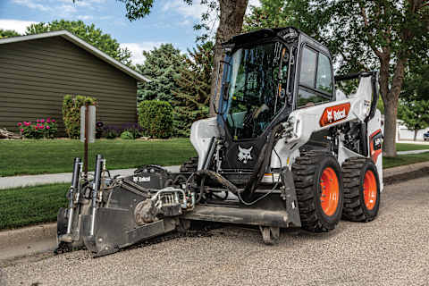An S64 Skid-Steer Loader With a Planer Attachment Works on a Residential Street