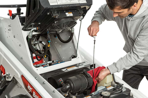 A Man Checks the Oil of a Bobcat MT100 Mini Track Loader