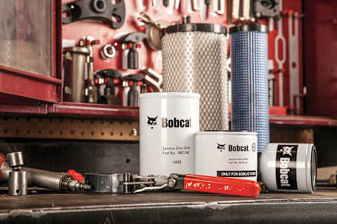 Bobcat Filters and Service Parts Displayed on a Workshop Bench With Maintenance Tools and Replacement Air Filters in the Background