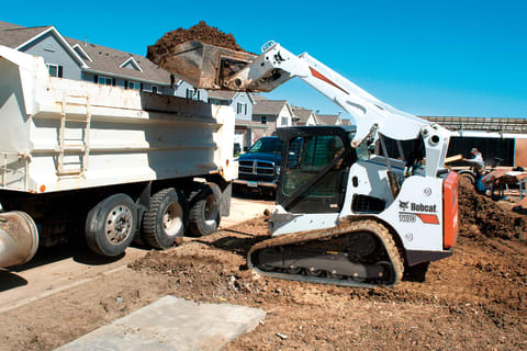 Bobcat T770 compact track loader loading dirt into high-sided dump truck