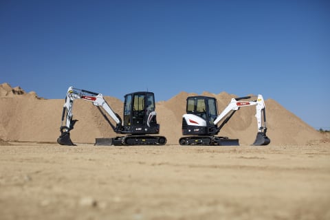 E32 and E35 Compact Excavators Parked on a Sandy Jobsite 
