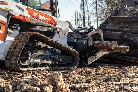 A Bobcat Compact Track Loader With 5-Link Torsion Suspension Undercarriage Lifts Materials on a Muddy Jobsite