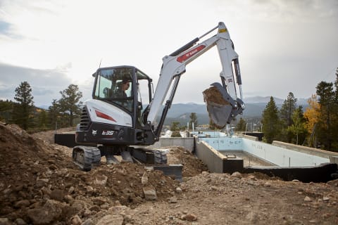 A Bobcat E35 Compact Excavator Perches on a Small Footprint of Land While Pulling Out Buckets of Dirt