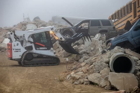 An operator with the National Search Dog Foundation uses a Bobcat T750 compact track loader with a grapple attachment. 