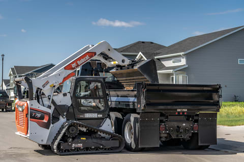 Operator Using Compact Track Loader With Bucket Loader Attachment