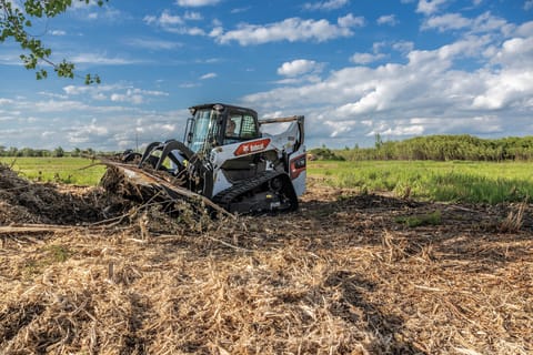 Cargadora Bobcat Serie R que retira raíces de árboles y maleza
