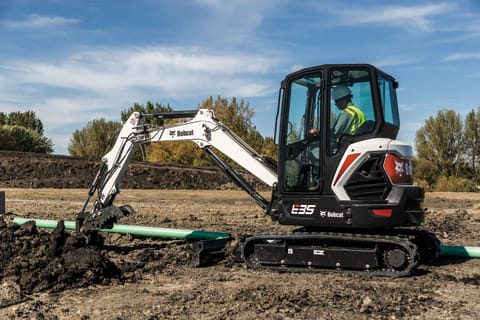 Bobcat E35 compact (mini) excavator and bucket attachment digging a trench