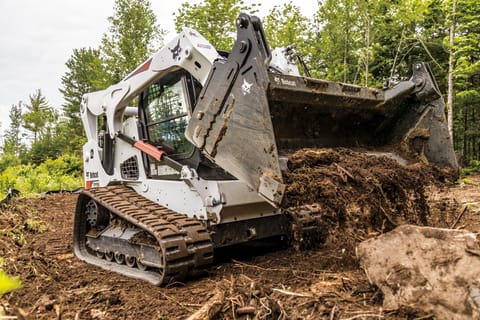 La cargadora compacta Bobcat T770 limpia tierra y rocas de un nuevo terreno de construcción.