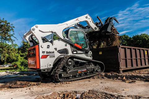 T870 compact track loader dumping a large load of debris into a waste container