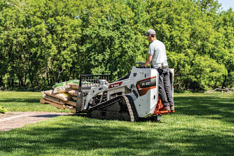 An Operator Carries a Pallet of Mulch Across an Established Lawn Using a Bobcat Mini Track Loader