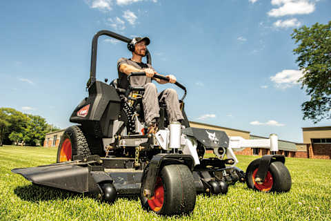 A Man Uses a Bobcat ZT6000 Zero-Turn Mower to Trim Grass Around a Commercial Building