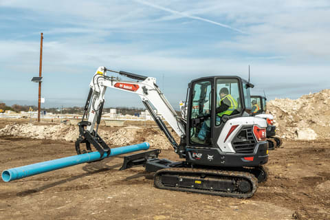 Bobcat E42 Compact Excavator Moving Pipe On Construction Jobsite